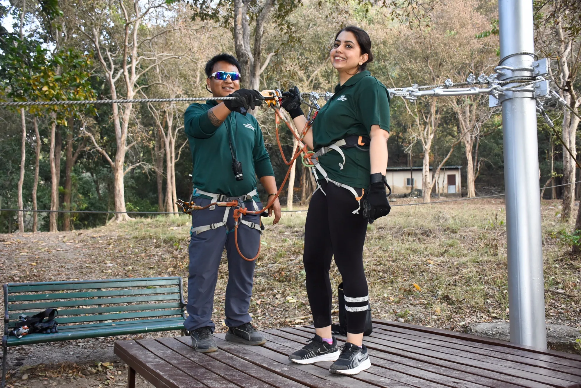 A smiling guest riding the zipline through the forest