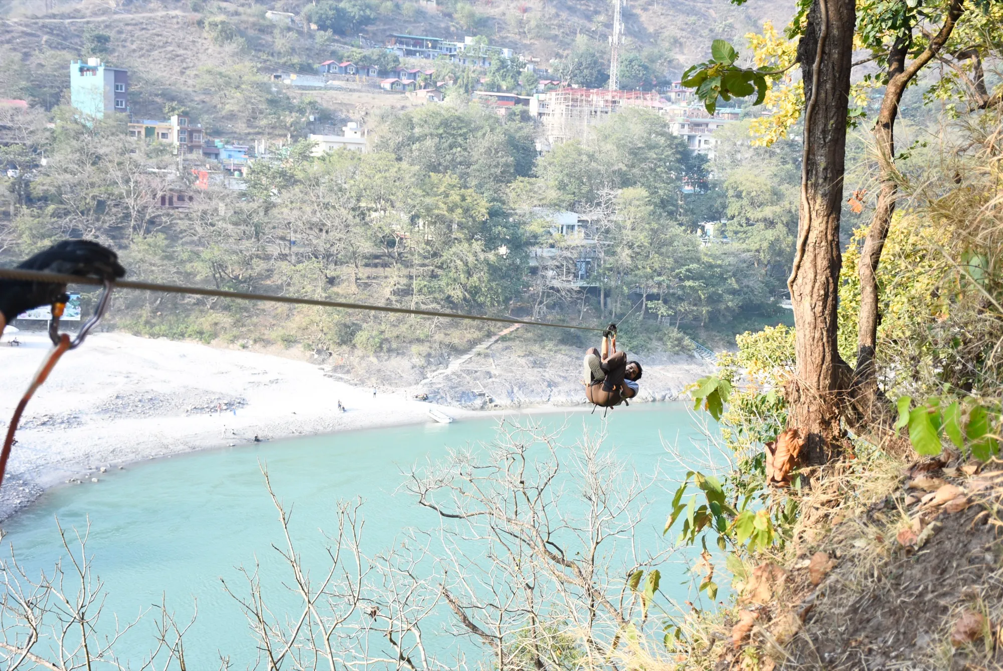 Instructor guiding a zipliner high above the Ganges