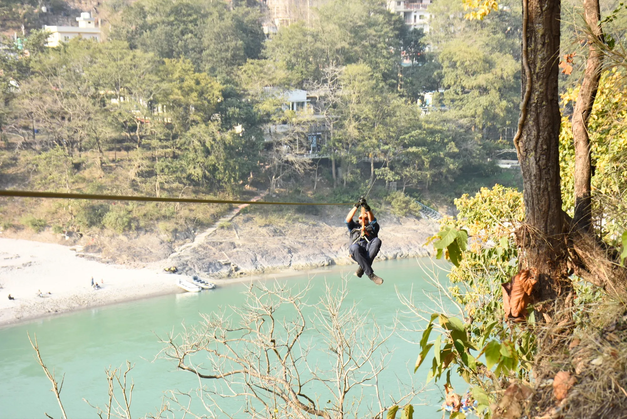 Zipliner soaring high above the turquoise Ganges